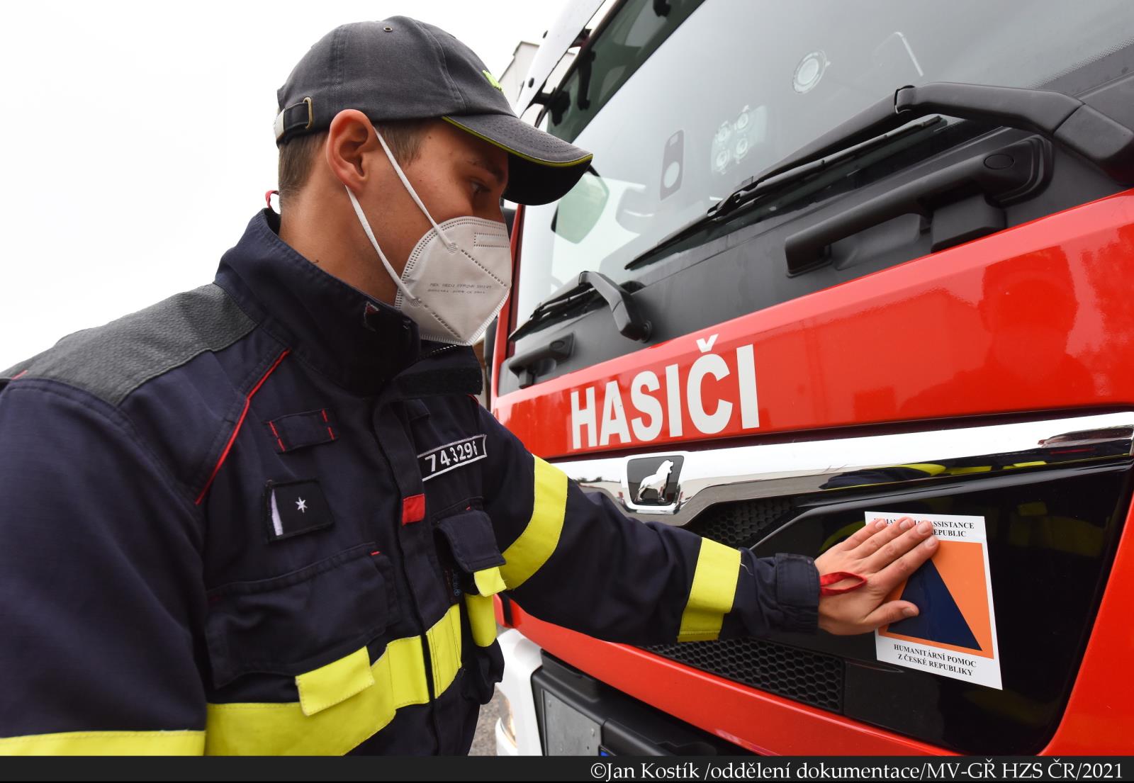 HP Lotyšsko_příslušník HZS ČR polepuje znakem humanitární pomoci náklad (3).JPG