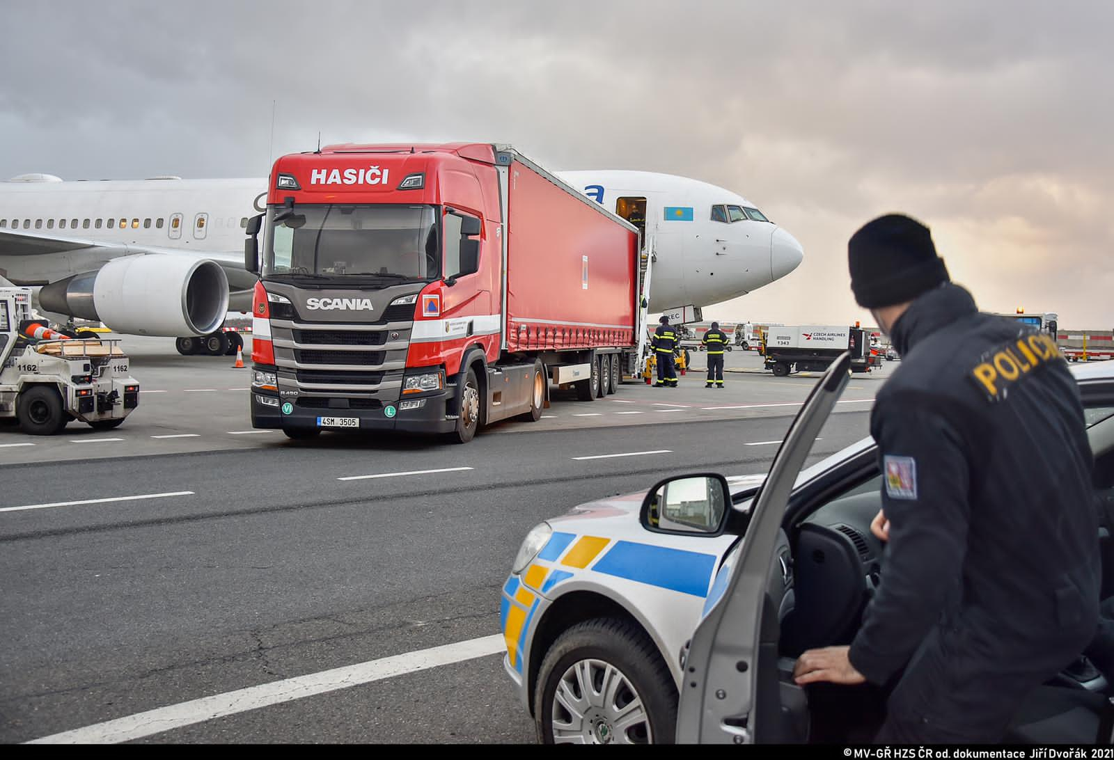 ZÚ_vykládka testů na covid na letišti Václava Havla_pohled na policistu nasedajícího do auta, letadlo a_2.JPG