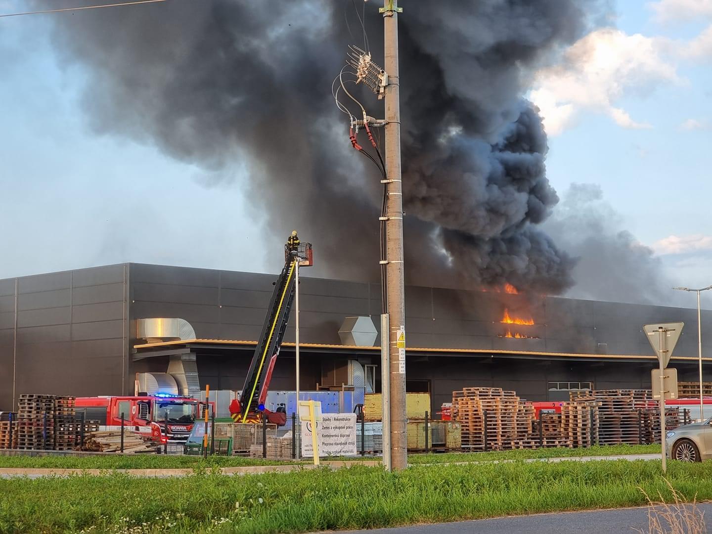 2_SČK_Požár hořovické lakovny_hustý černý dým stoupající ze střechy haly a zasahující jednotky zasičů.jpg