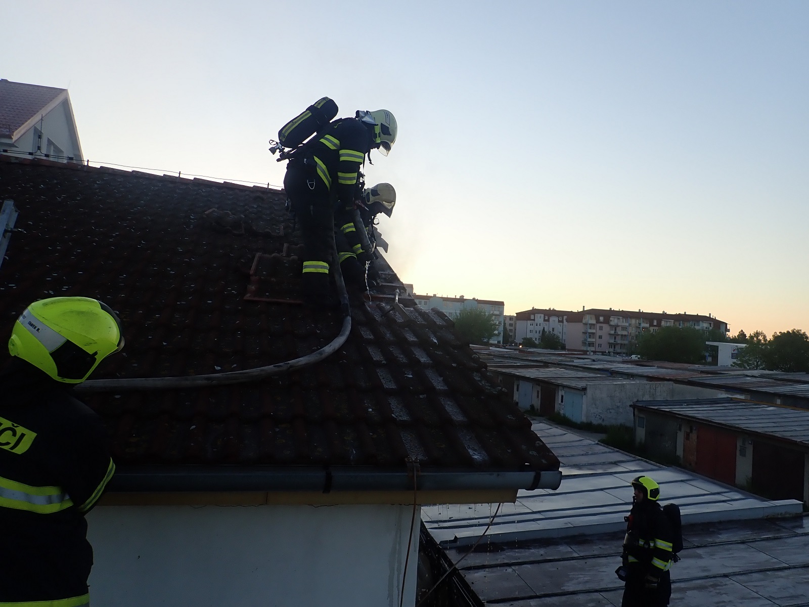 Hasiči rozebírají část střechy sousedního objektu